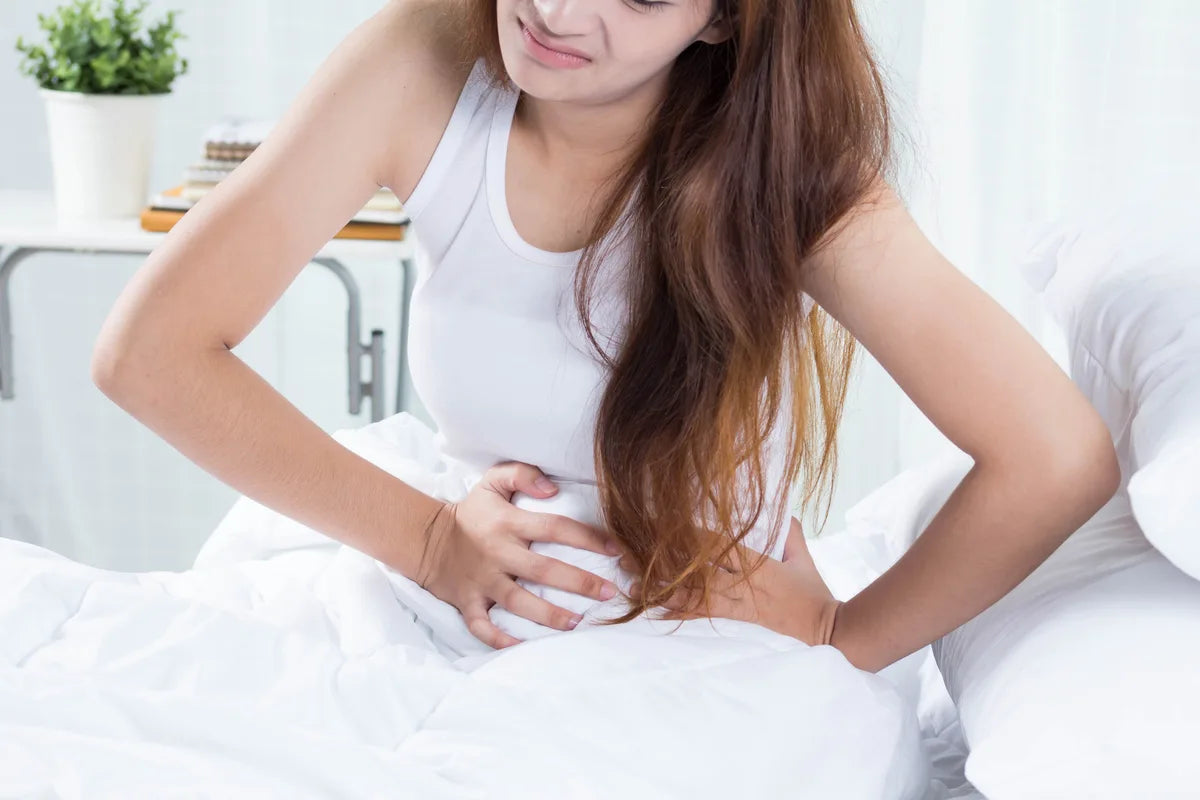 woman sitting on her bed and holding her painful tummy due to UTI