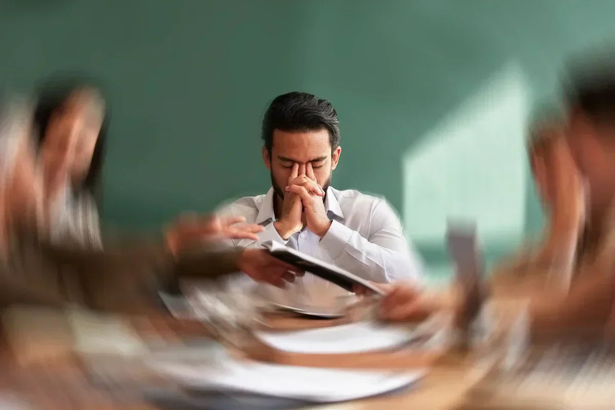 man holding his temples and experiencing anxiety, feeling like everything around him is rotating