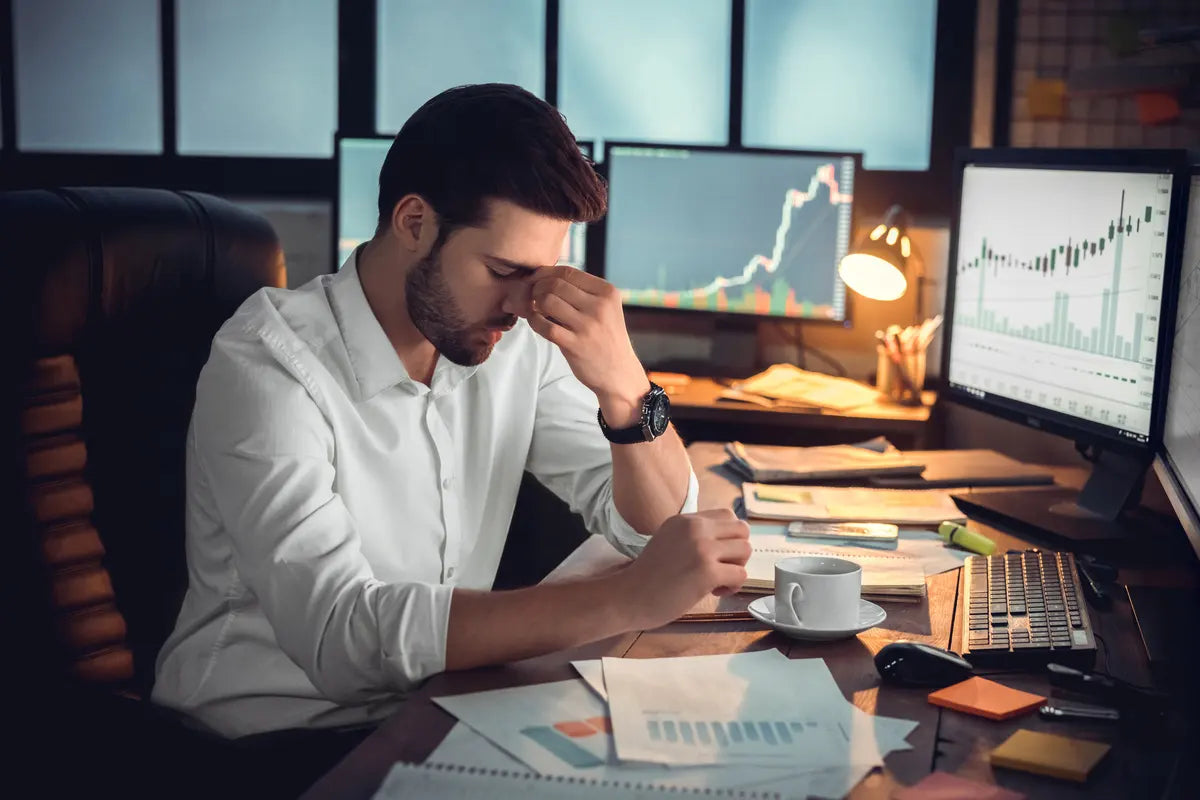 man sitting in front of his computer and pressing his temples due to stress