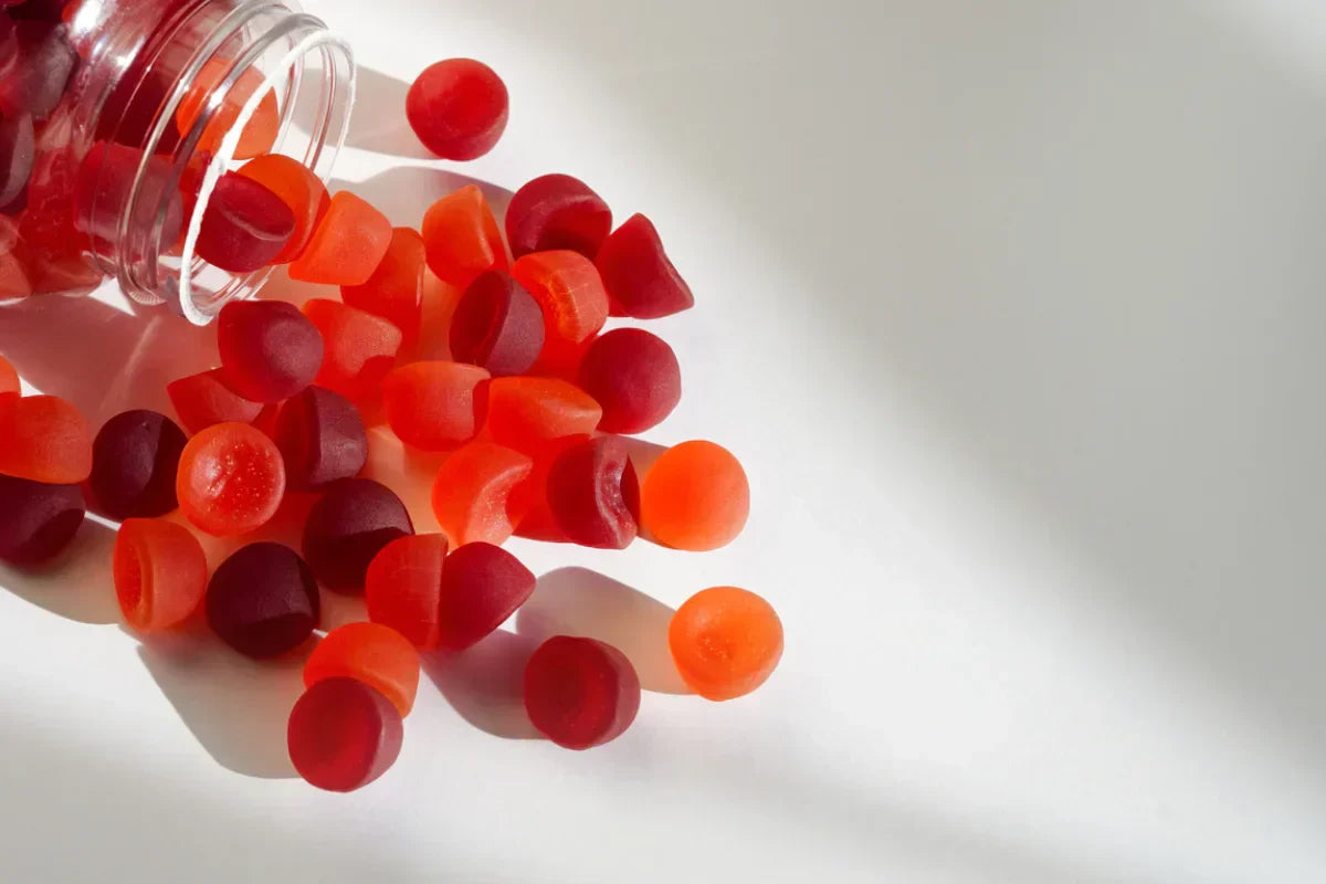 a number of daily multivitamin gummies spilling out from its bottle on a table