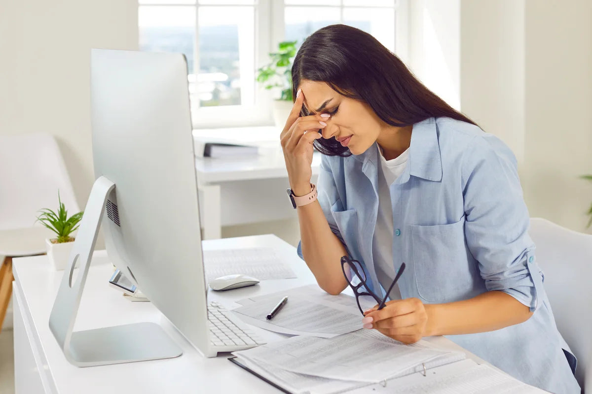 woman in front of her computer experiencing migraine