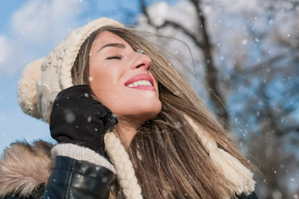 woman with healthy straight blond hair covered in bonnet enjoying the snow