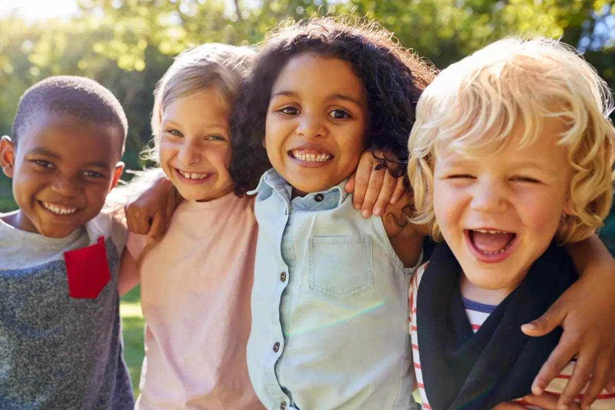 four children with arms one each other's shoulders looking happy and energetic