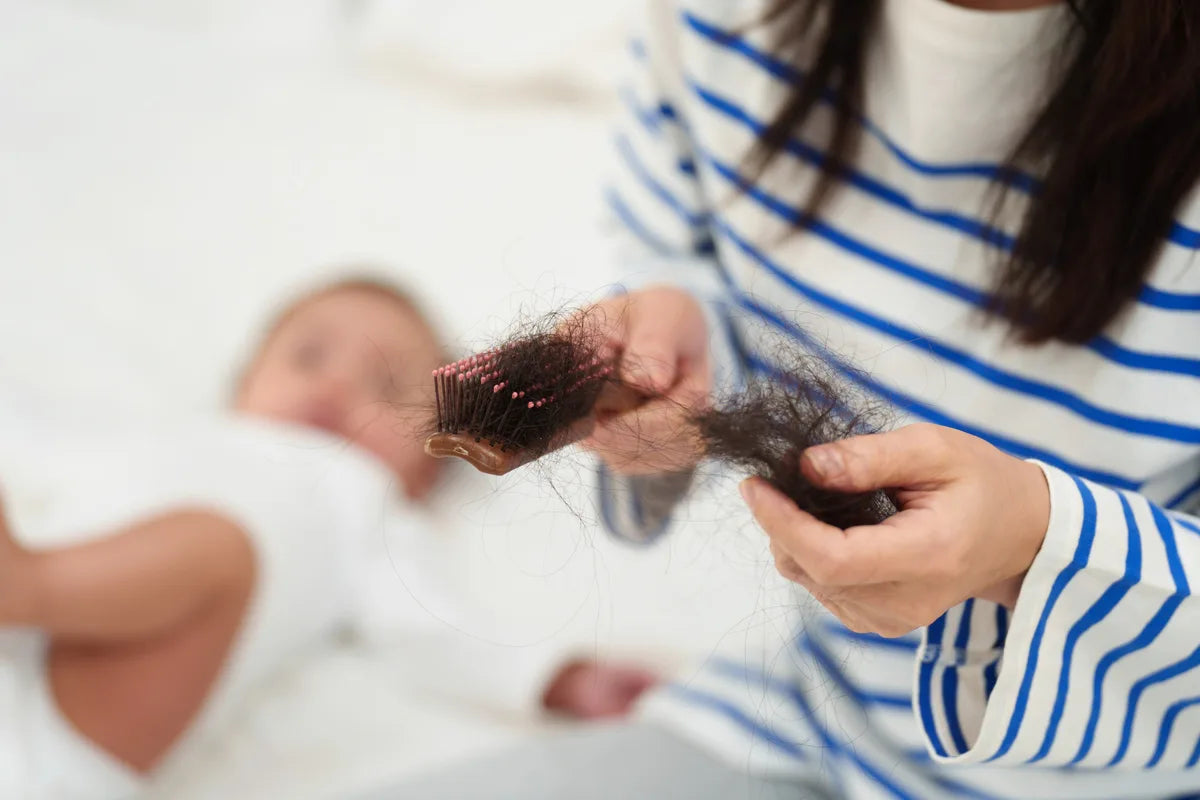 a mom next to her baby experiencing postpartum hair loss