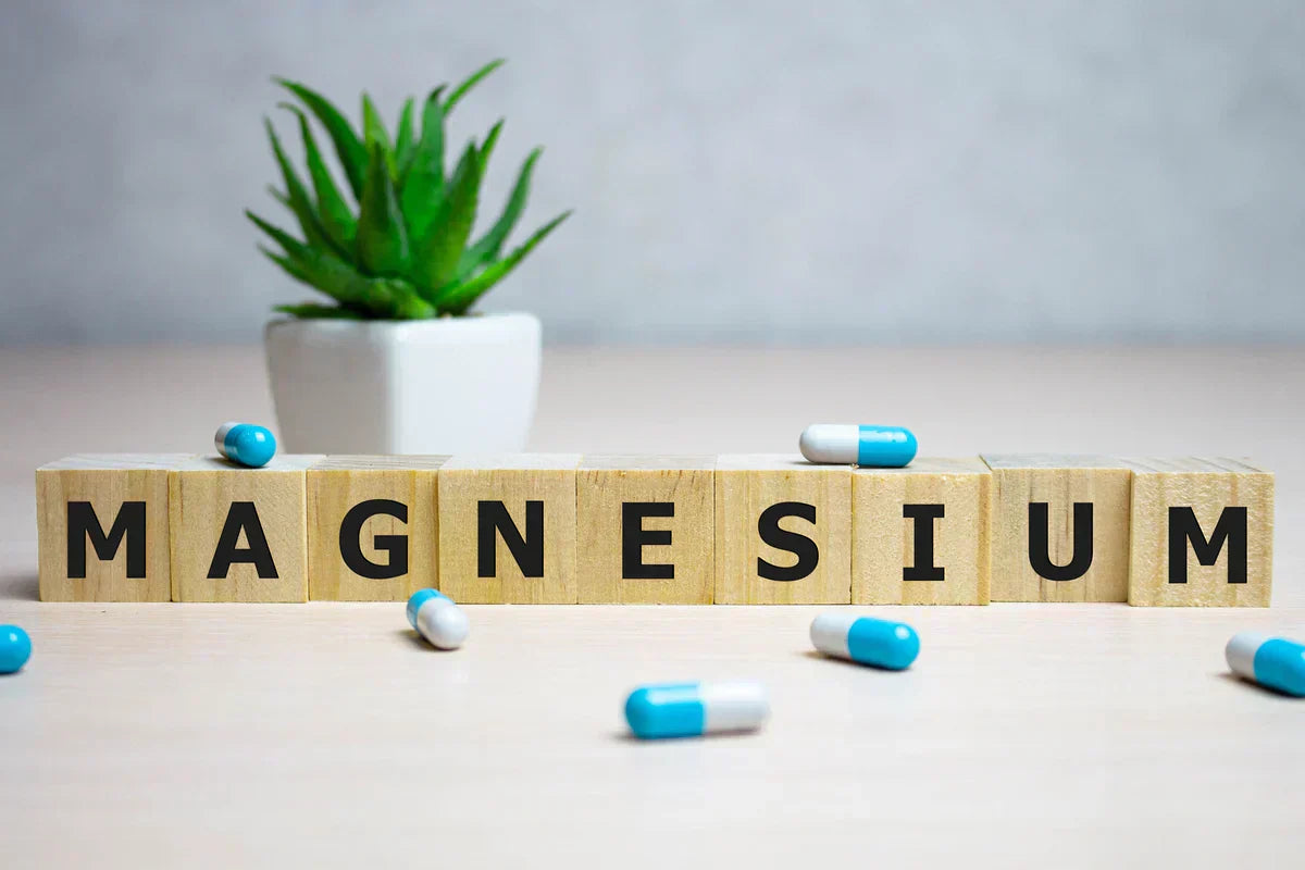 blocks of letters forming the word magnesium with magnesium complex pills around it