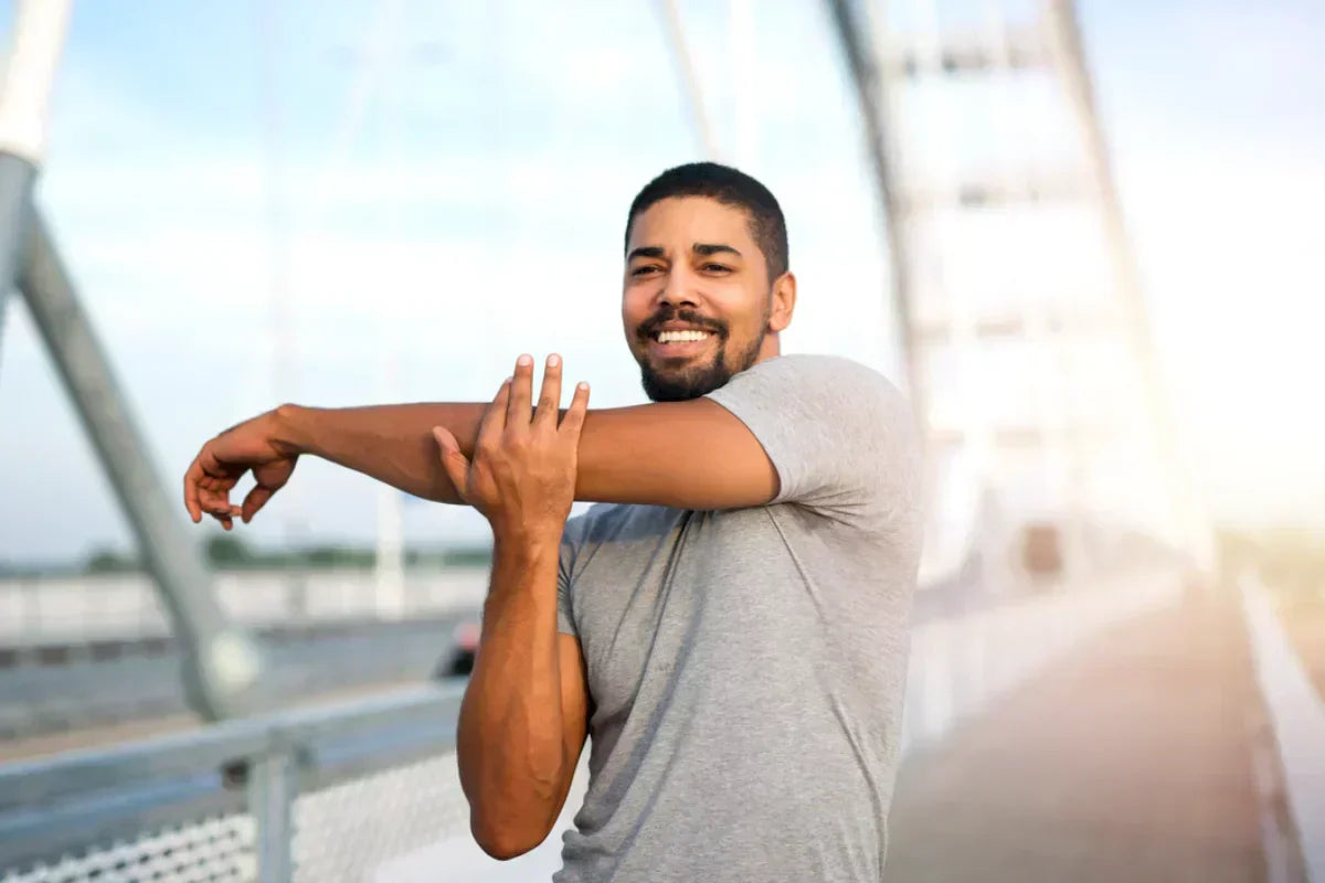 man doing stretching at a bridge with a bright smile and improved mood