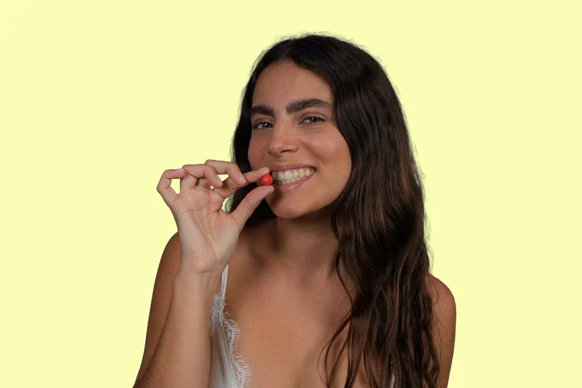 woman looking at the camera and holding a Multivitamin Gummy near her mouth