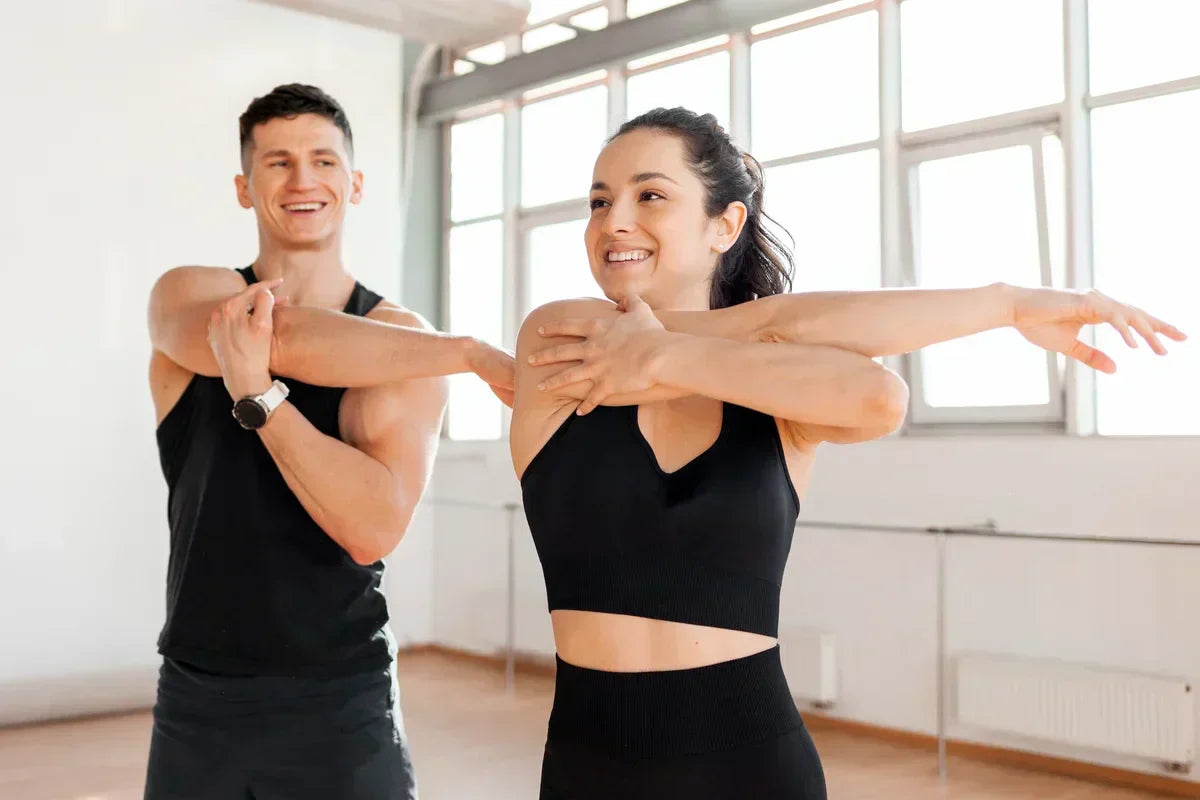 man and woman doing light stretches at the gym for faster muscle recovery