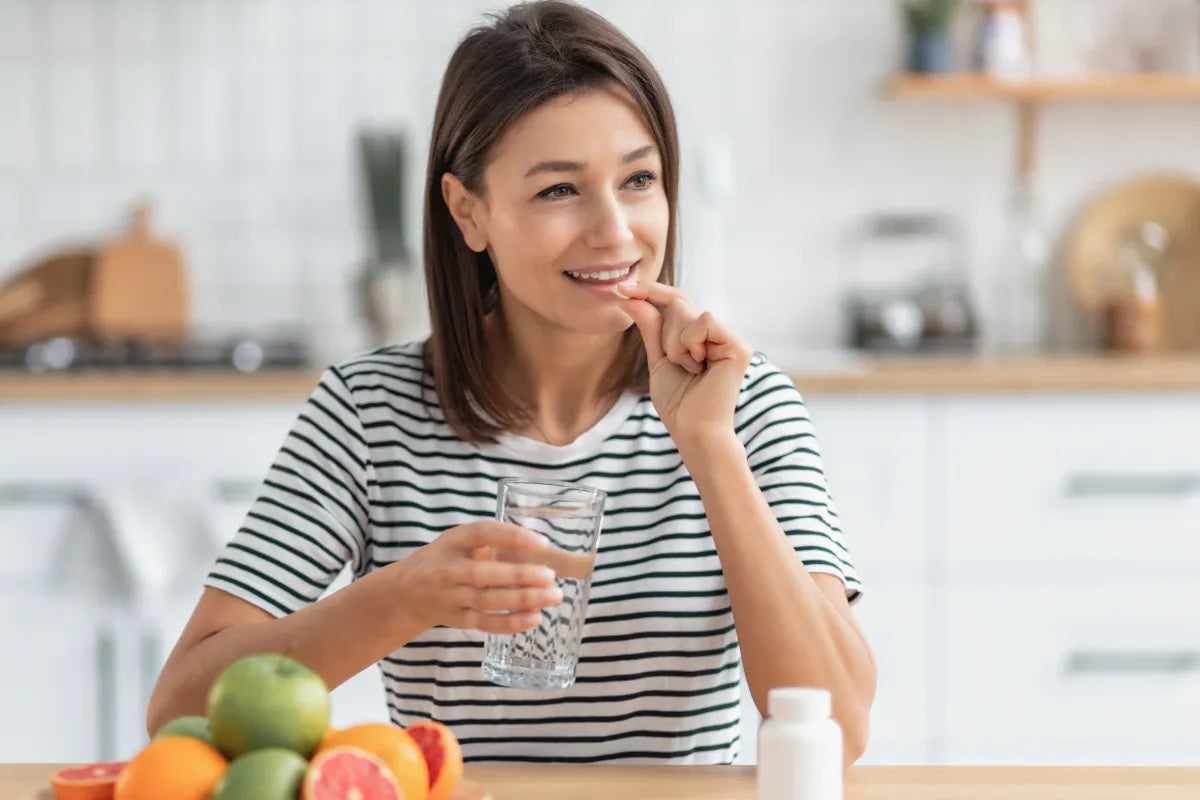woman taking acv pills while sitting by the table