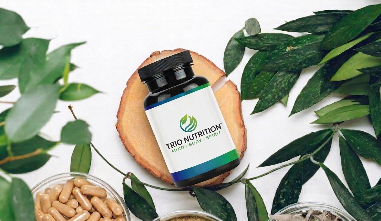 Trio Nutrition supplement bottle on a wood slice with capsules, herbs and botanicals — premium vitamins and supplements manufactured in the USA
